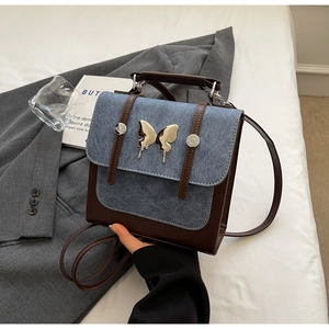 Macro view of blue suede flap with silver butterfly buckle on a two-tone square backpack