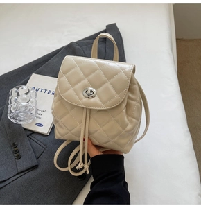 Close-up of quilted cream backpack with silver twist lock and drawstring closure