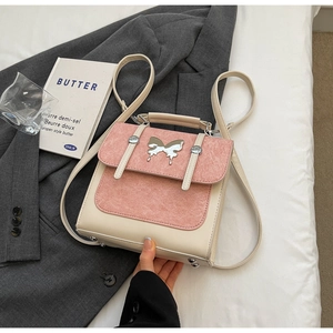 Detail of a two-tone backpack featuring a pink flap and silver butterfly logo on a grey suit