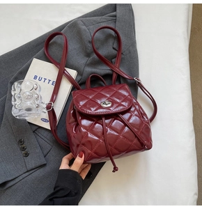 Detail view of burgundy quilted mini backpack with drawstring and turn-lock closure