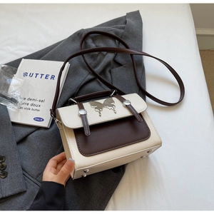 Détail d'un sac messager bicolore avec boucle papillon et clous de protection métalliques
