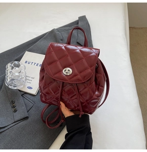 Detail showing burgundy quilted leather texture and silver clasp on mini backpack