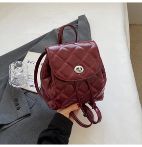 Detail of burgundy quilted leather backpack featuring silver twist lock and glossy texture