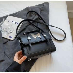 Détail du sac à main noir en simili cuir avec papillon argenté et sangles à boucles