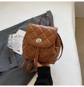 Close-up of brown quilted backpack with silver twist lock and drawstring closure