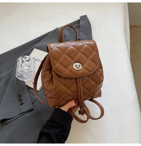 Detail of a brown quilted leather mini backpack with metal twist lock and drawstring closure