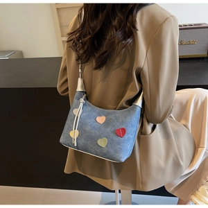 Detail shot of blue denim crossbody bag featuring colorful heart patches and long tassels