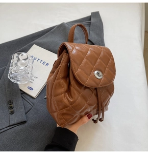 Detail of brown quilted mini backpack with turn-lock closure and leather texture