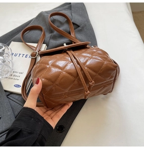 Detail of brown quilted faux leather backpack with high-gloss texture and vintage buckle