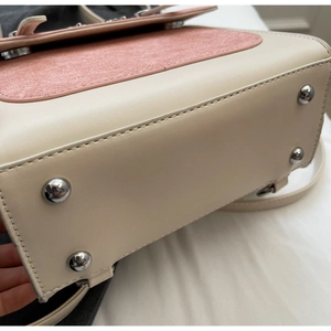 Close-up of contrast stitching, metallic base studs, and dual-texture material on the bag