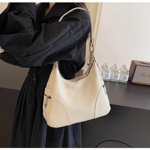 Detail of cream hobo bag showing litchi grain leather texture and functional side zipper
