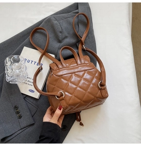 Top view of brown quilted PU leather backpack on a grey suit with metallic buckles