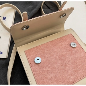 Detail of beige and pink crossbody bag showing double magnetic closures and front suede pocket
