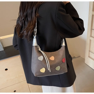 Close-up of heart-shaped multi-color patches and hand-stitched details on grey bag