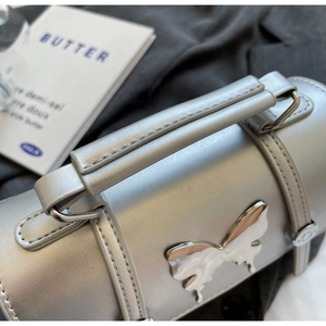 Détail du sac argenté avec boucle papillon en métal et incrustation marbre blanc