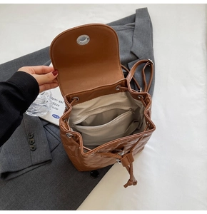 Interior view of brown quilted backpack showing drawstring closure and inner zip pocket