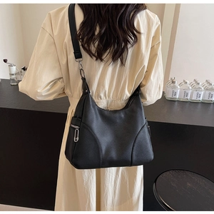 Detail of black hobo bag showing litchi leather texture and silver safety pin zipper pull