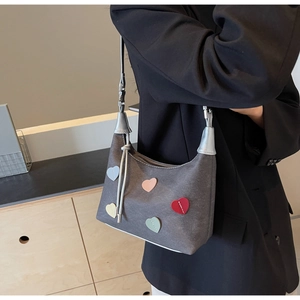 Detail of grey matte shoulder bag featuring colorful heart patches and stylish tassel zipper