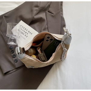 Detail of spacious interior in a beige crescent bag holding phones and cosmetics