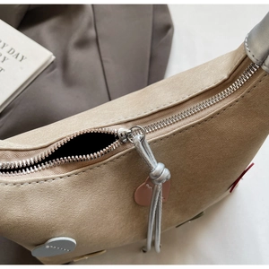 Detailed close-up of khaki dumpling bag with silver knot zipper and heart charm
