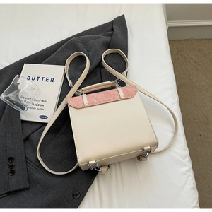 Detail view of contrast color faux leather backpack on white sheets with aesthetic props