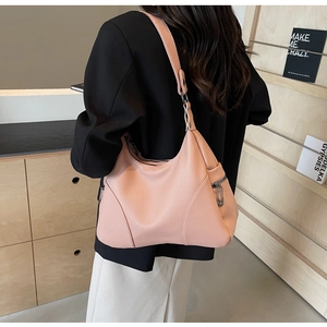 Detail view of pink lychee texture leather shoulder bag worn by model in a cozy setting
