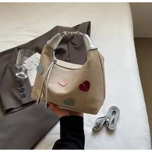 Detail of khaki heart-embellished dumpling bag with silver handles and detachable strap