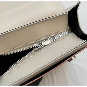 Detail of silver zipper hardware and contrast black lining on beige fashion backpack