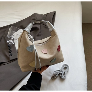 Detail of khaki suede hobo bag featuring colorful heart patches and silver metal handles