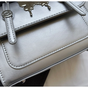 Détail d'un sac bandoulière argenté avec fermoir papillon et texture en similicuir PU