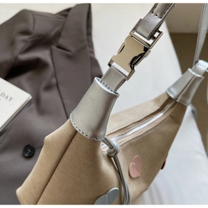 Detailed shot of khaki canvas bag with heart patches and shiny silver metal buckle