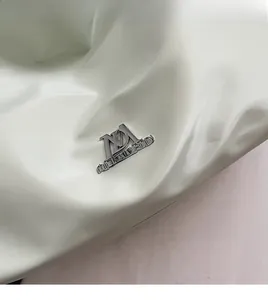 Nahaufnahme des silbernen Metalllogos und der weichen PU-Lederstruktur der grünen Tasche