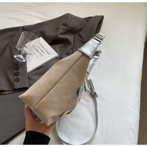 Detail showing khaki suede and silver leather shoulder bag with a heart badge on bedside