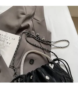 Detail of black pleated bucket bag with crystal handle and skull heart ornaments
