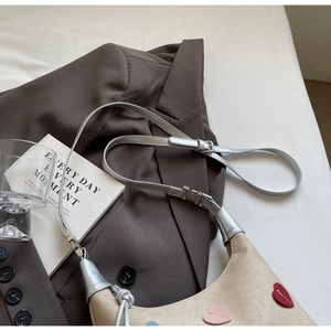 Detail of khaki heart-patterned tote bag with metallic strap on brown blazer