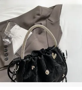 Detail of black velvet bucket bag with rhinestone handle and metallic heart charms