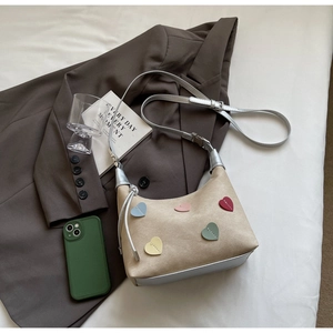Detail of apricot suede half-moon bag with colorful heart patches and silver metallic strap