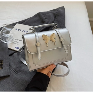Détail du mini sac bandoulière argenté avec grand ornement papillon métallique