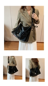 Detail der schwarzen Lack-Tote-Bag mit M-Logo aus Metall und breitem Schultergurt