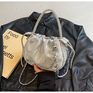 Detail of silver pleated bucket bag with rhinestone handle and saturn charm pendant