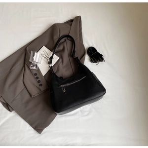 Detail of black lychee grain hobo bag with back zipper pocket on a dark blazer