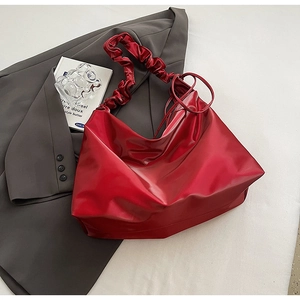 Detail der roten Oversize-Tasche aus glänzendem Leder mit gerafftem Schulterriemen