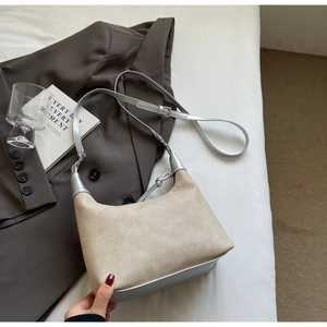 Detail of minimalist hobo bag showing contrast of matte beige and metallic silver textures