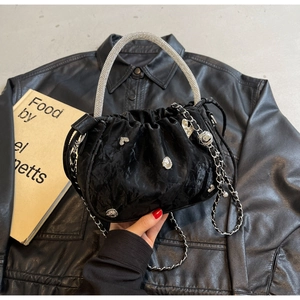 Detail of black velvet pleated bucket bag with rhinestone handle and metallic charms