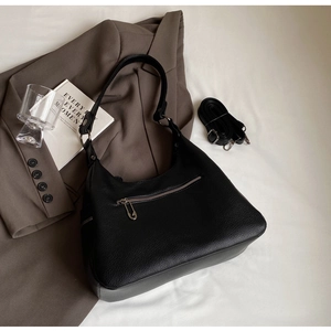 Detail of black lychee grain crescent bag with silver zipper and dual strap options