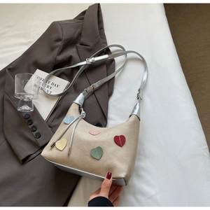 Detail of half-moon beige handbag with colorful heart patches and silver strap