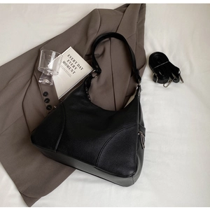 Detail of black lychee texture hobo bag with adjustable strap on a blazer