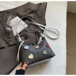 Detail of grey canvas shoulder bag with colorful heart patches and silver straps