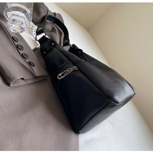 Close-up of black lychee-grain leather underarm bag featuring silver metal zippers
