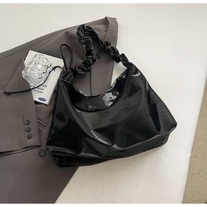 Makro-Detail der schwarzen Lackleder-Hobo-Tasche mit Falten-Griff und Kordelzug-Design